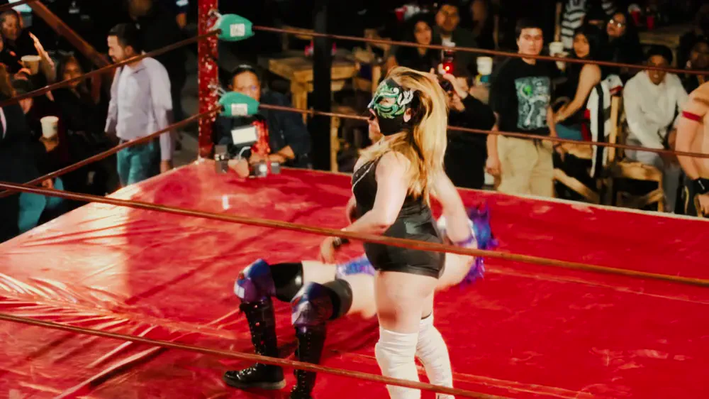 Luchadora sobre el ring rojo frente al público